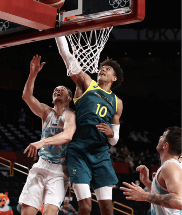 two basketball players in different jerseys jumping towards a basketball hoop