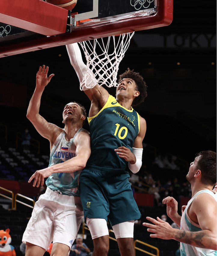 two basketball players in different jerseys jumping towards a basketball hoop