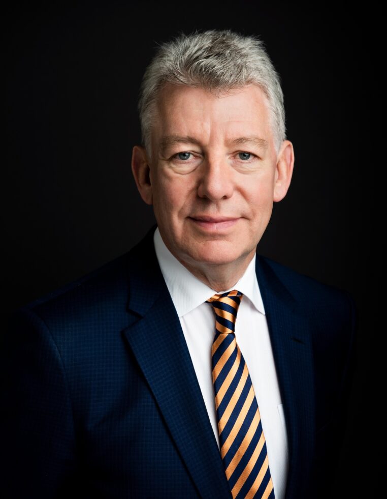 portrait of a man with gray hair in a navy suit on a black background