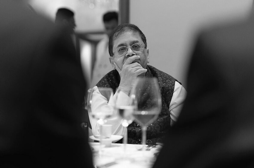 Cyril Shroff sitting at a dinner event contemplating another speaker