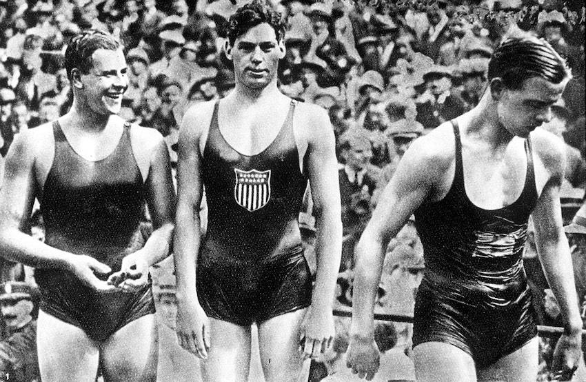 An old grainy black and white photograph of three men in retro swimsuit leotards. 