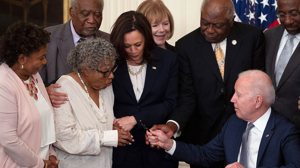 President Joe Biden hands the “Grandmother of Juneteenth,” Dr. Opal Lee, the pen with which he signed the Juneteenth National Independence Day Act in the White House surrounded by Vice President Kamala Harris among others.