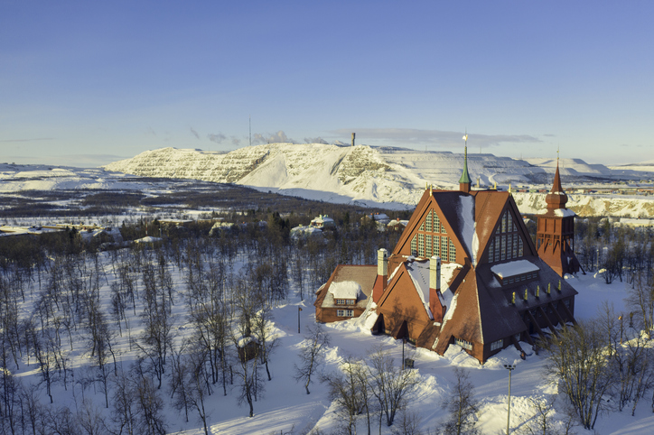 An image of Kiruna Church, a landmark building built in wood in the town of Kiruna in the northern province of Lapland, Sweden. In the background is the iron mining operations in the town.