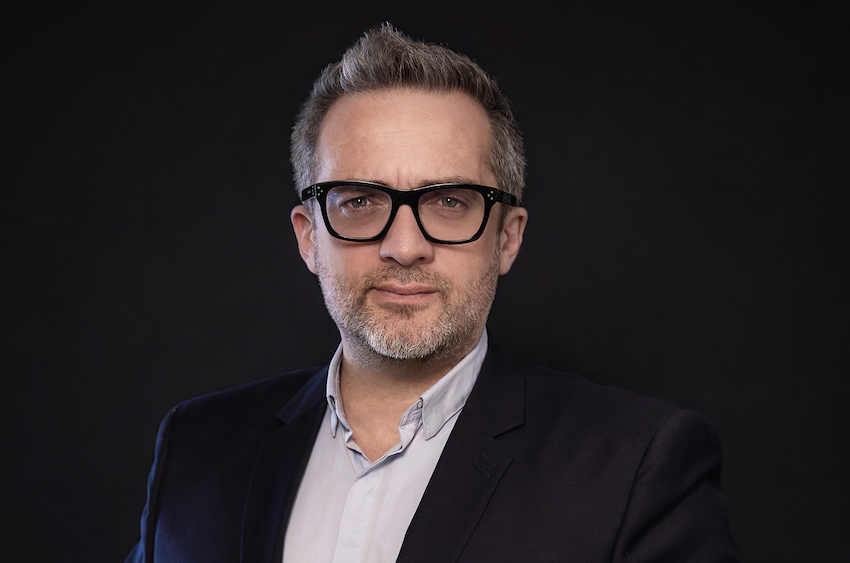 Portrait photo of Emmanuel Vivier, a man wearing glasses with gray hair and a short beard wearing a navy suit jacket