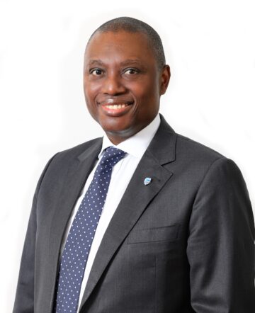 Headshot of Standard Bank CEO Sim Tshabalala wearing a gray suit with a white shirt and navy tie with white polka dots