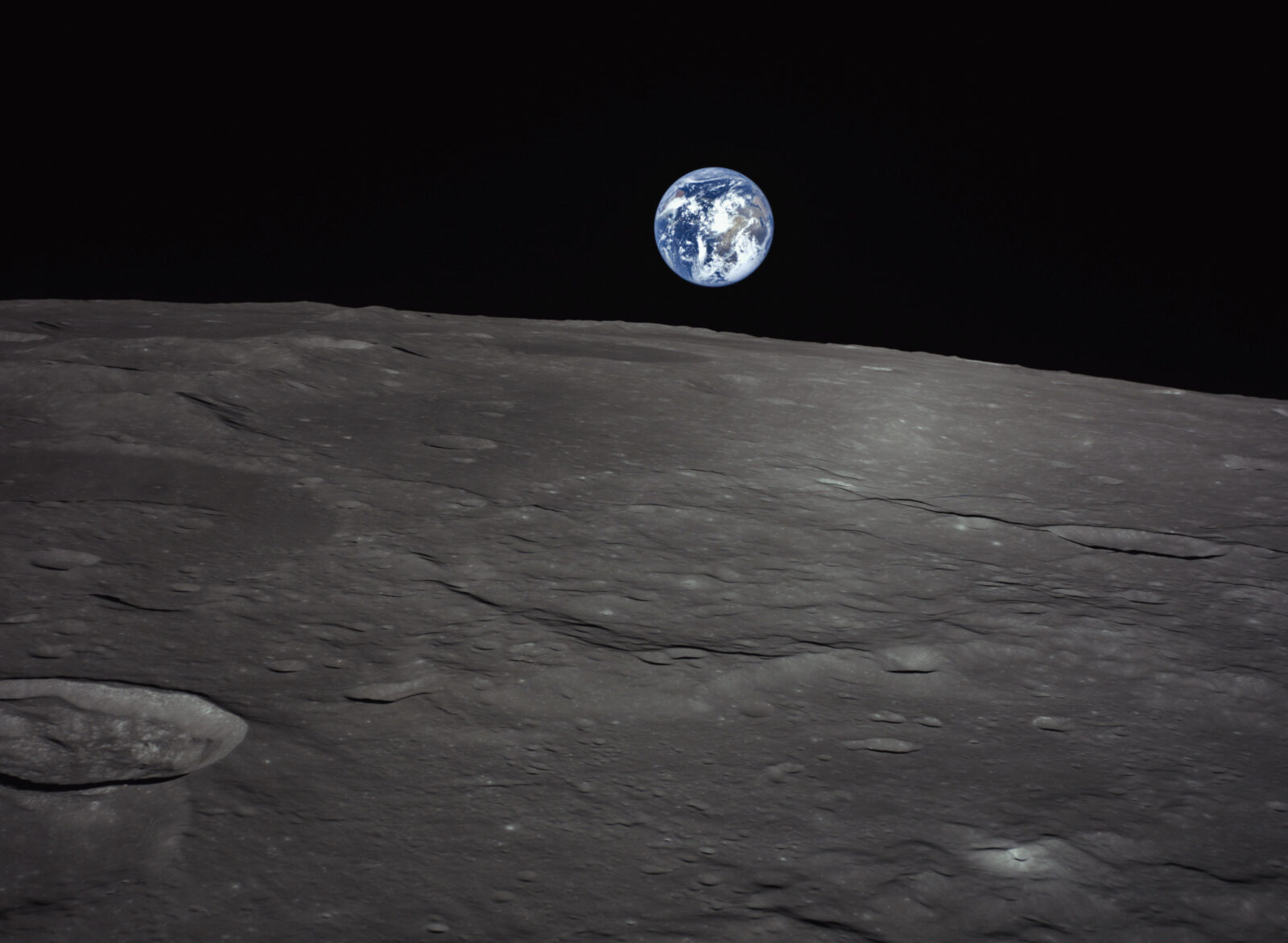 A photograph taken from a robotic lander orbiting the Moon capturing a view of the lunar landscape with Earth on the horizon.