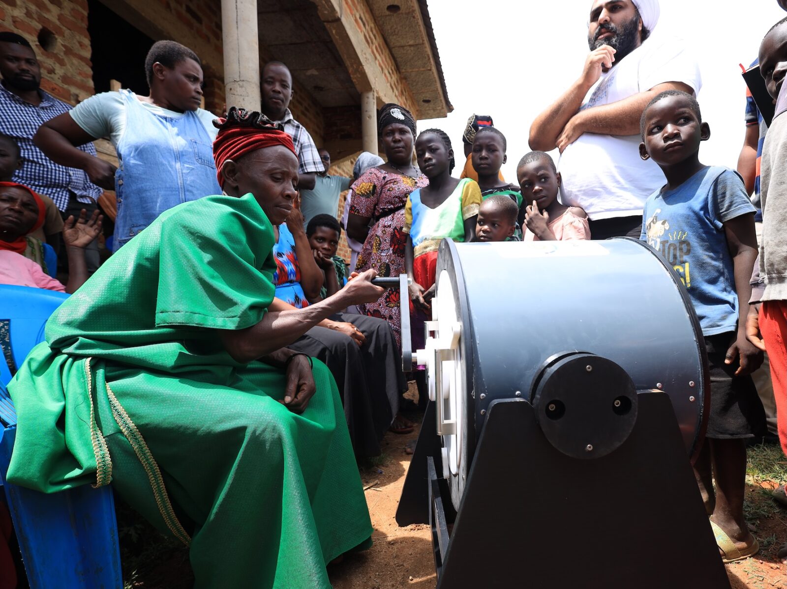 Community members in rural Uganda, hand-cranking the Divya washing machine