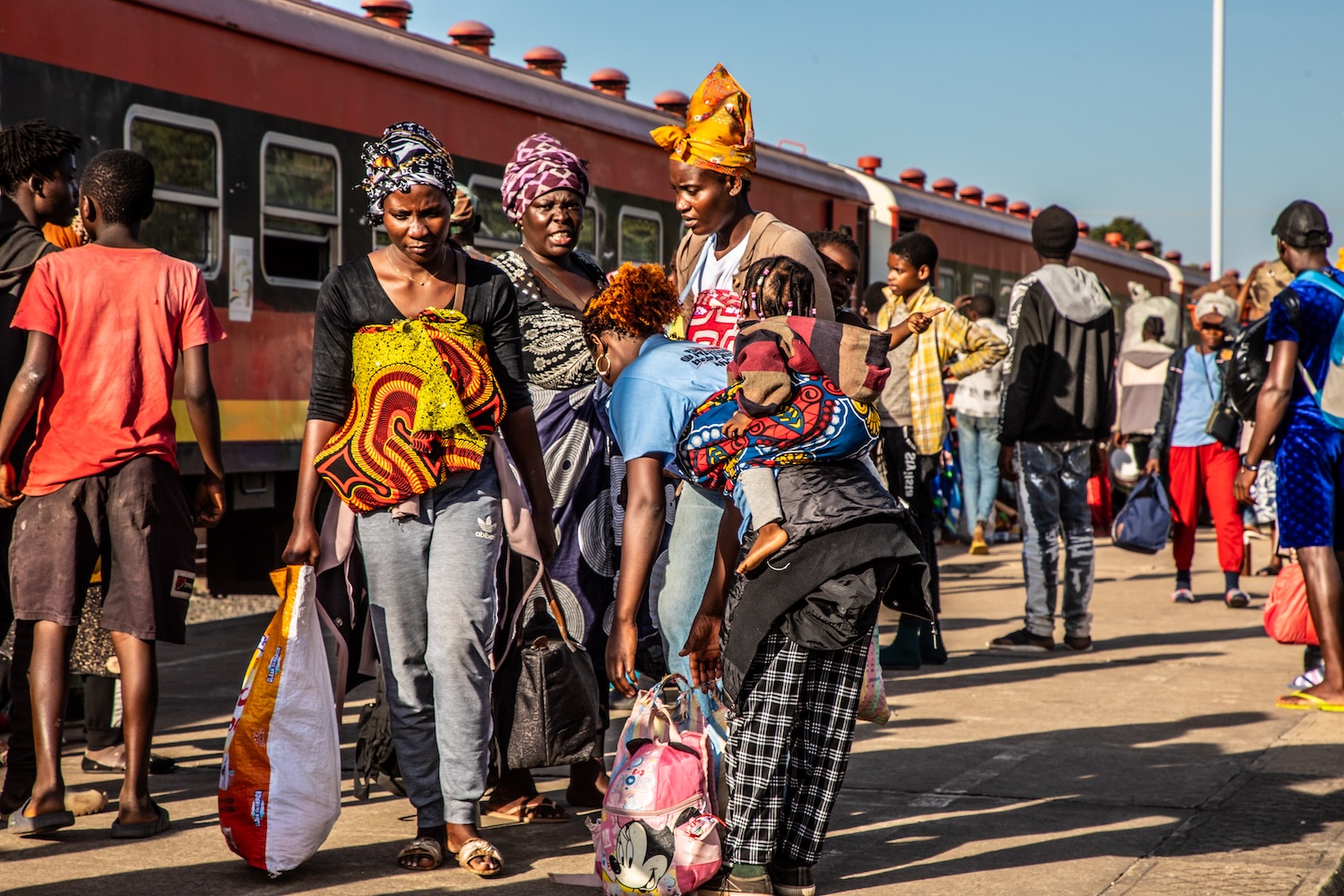a group of African American women standing outside a train lugging bags away from the train