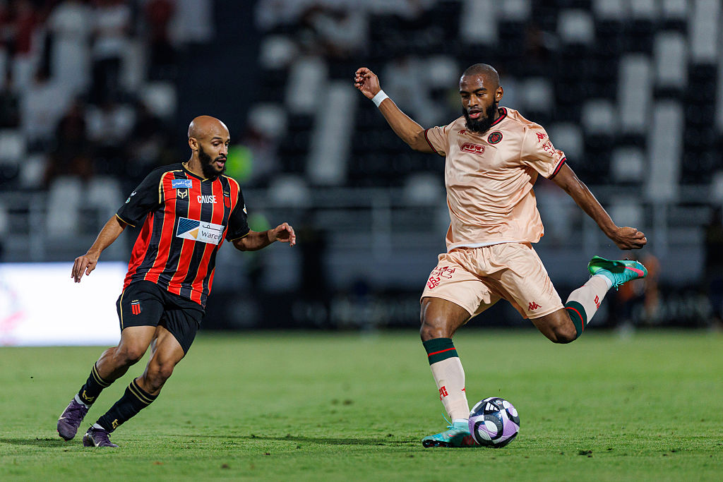 photograph of two middle eastern futbol players on the field during a match