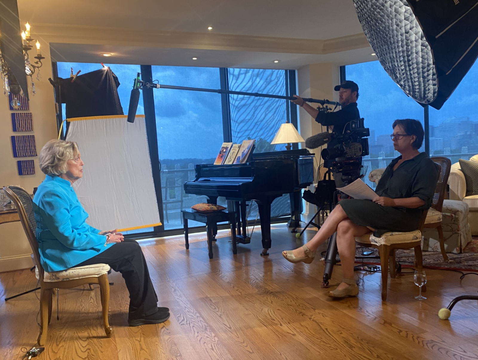 an image of two women facing each talking with cameras and lighting surrounding them.