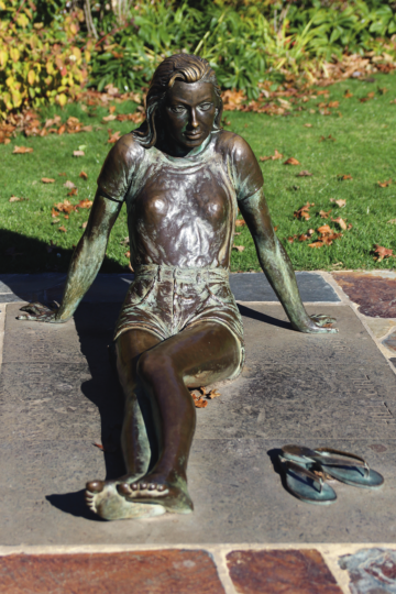 a photograph of a bronze statue of a woman laying down