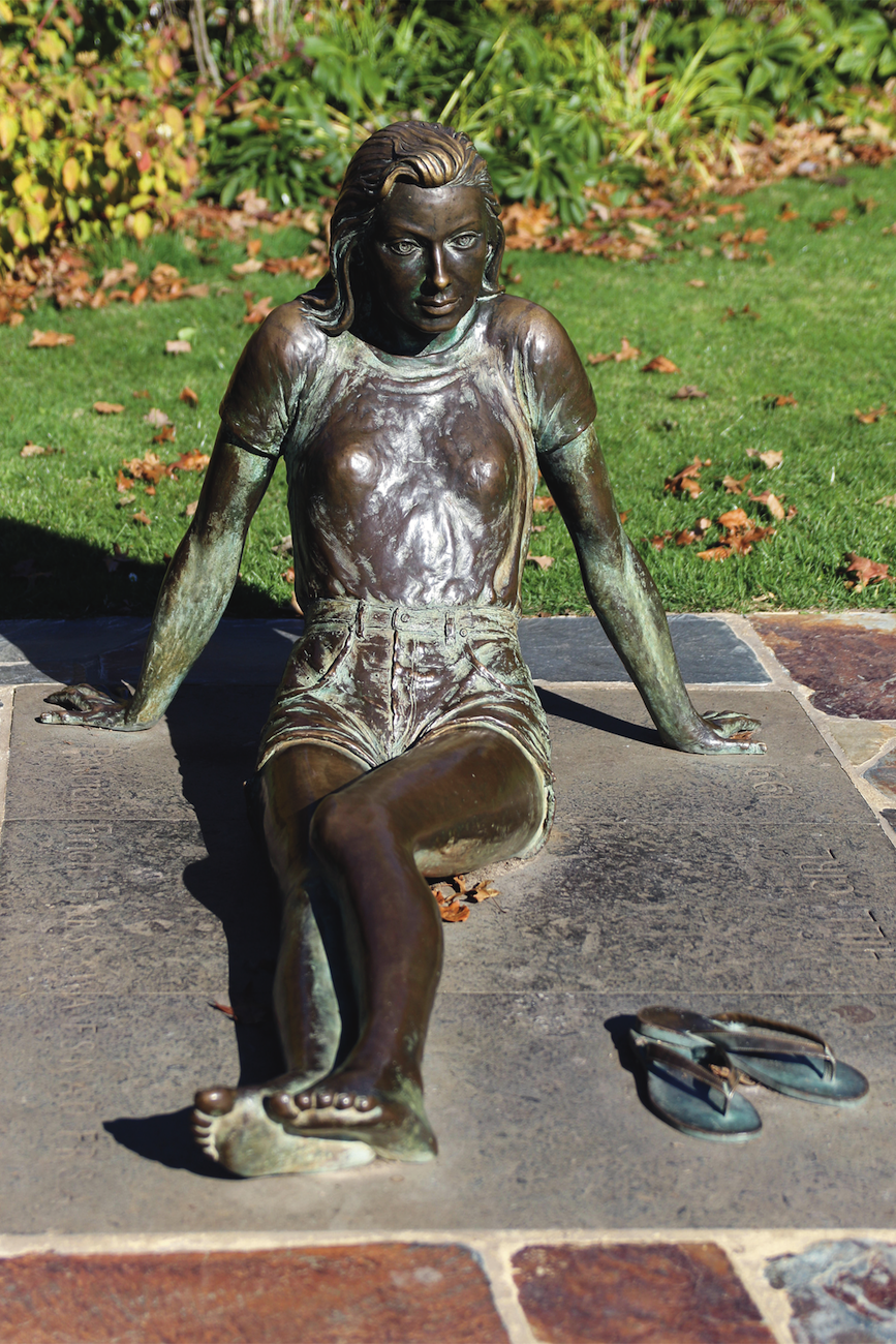 a photograph of a bronze statue of a woman laying down