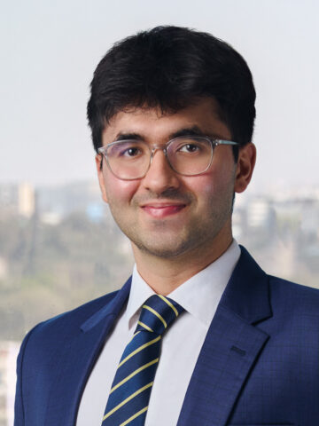 headshot image of a young man wearing a navy suit and glasses