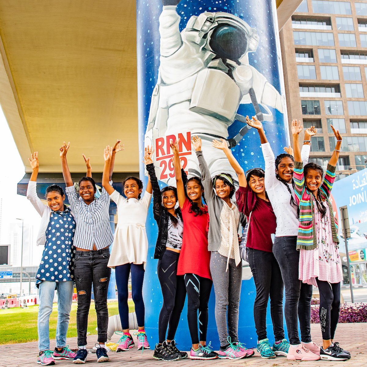 a photo of a nine girls smiling with their hands raised above their heads